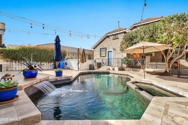 view of swimming pool featuring a pool with connected hot tub, fence, and a patio