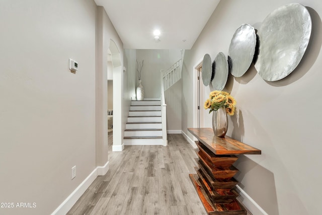 hall featuring light wood-style floors, stairway, and baseboards