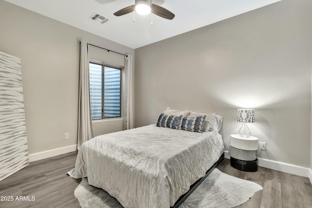 bedroom featuring baseboards, visible vents, ceiling fan, and wood finished floors