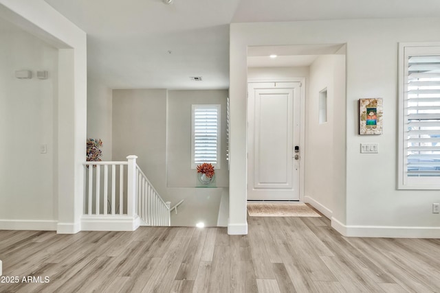 foyer featuring baseboards, visible vents, and light wood finished floors