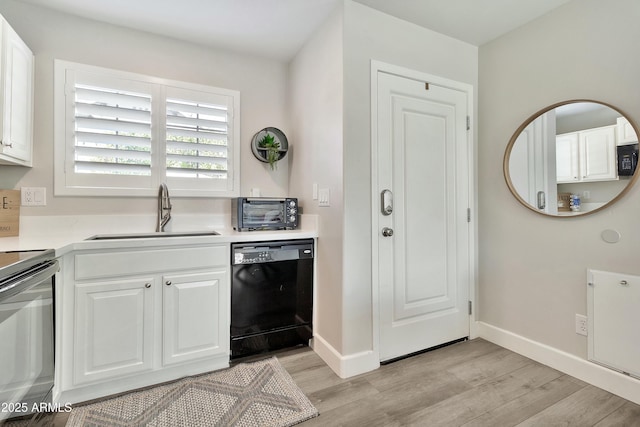 kitchen featuring light wood-style flooring, a sink, white cabinets, light countertops, and black appliances