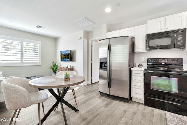 kitchen featuring light countertops, visible vents, white cabinetry, light wood-type flooring, and black appliances