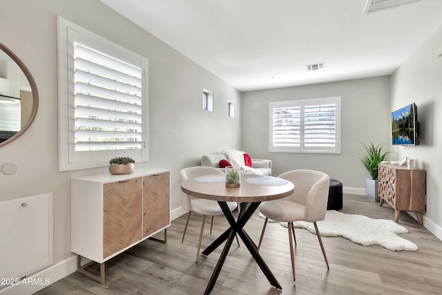 dining area featuring wood finished floors, visible vents, and baseboards