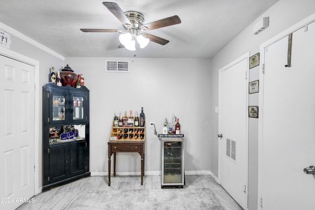 bar featuring wine cooler, a textured ceiling, and ceiling fan