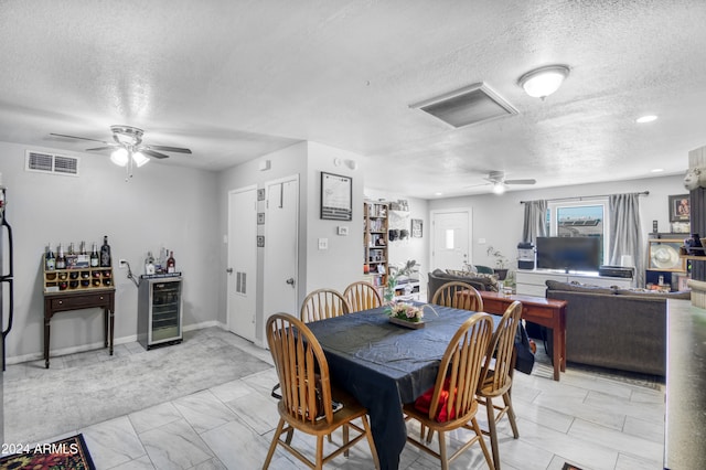 dining space featuring ceiling fan, wine cooler, and a textured ceiling