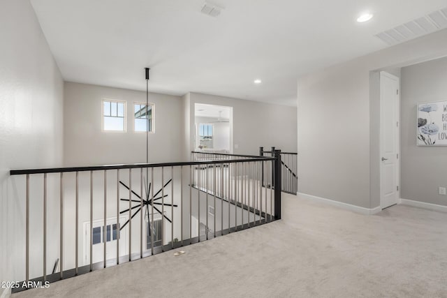 hallway with baseboards, visible vents, carpet flooring, and an upstairs landing