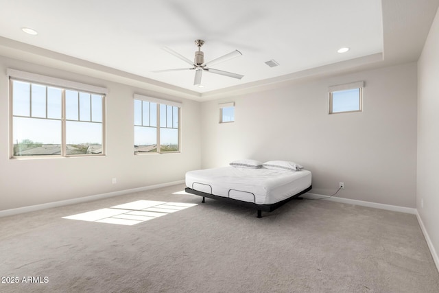 bedroom with a tray ceiling, carpet flooring, visible vents, and baseboards