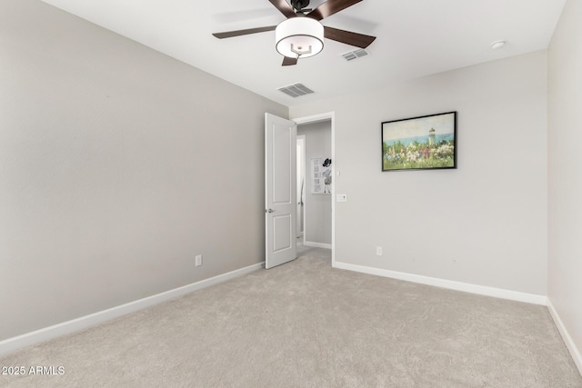 spare room with light colored carpet, visible vents, ceiling fan, and baseboards