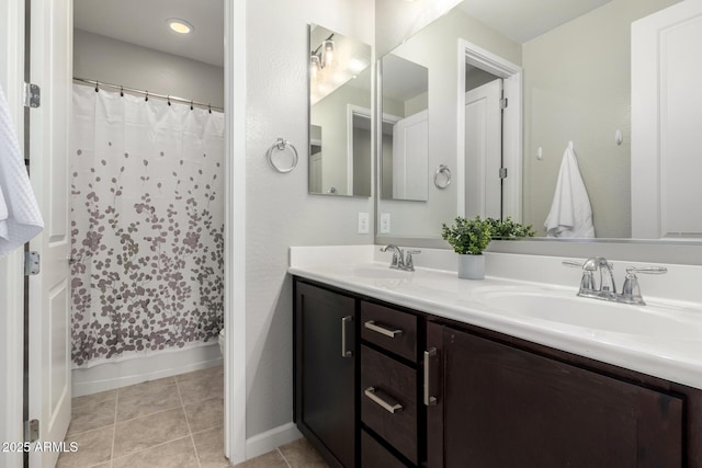 full bathroom featuring double vanity, tile patterned flooring, baseboards, and a sink