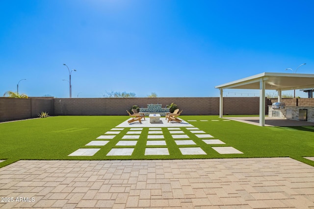 view of yard featuring exterior kitchen, a patio area, a fenced backyard, and a fire pit