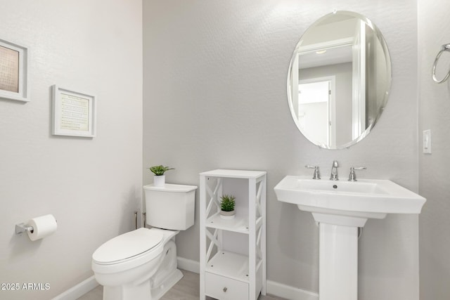 bathroom with baseboards, a sink, and toilet