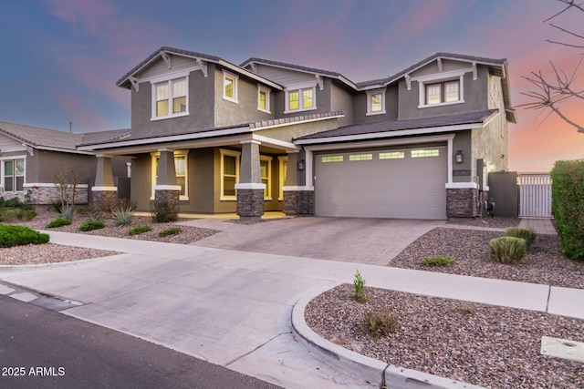 craftsman house with a garage, stone siding, fence, decorative driveway, and stucco siding