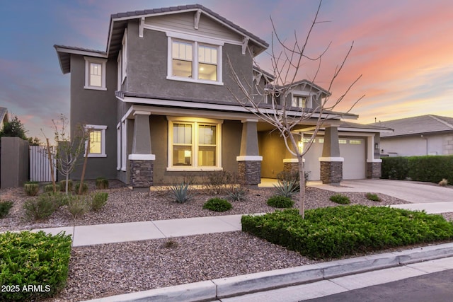 craftsman house with driveway, stone siding, an attached garage, fence, and stucco siding