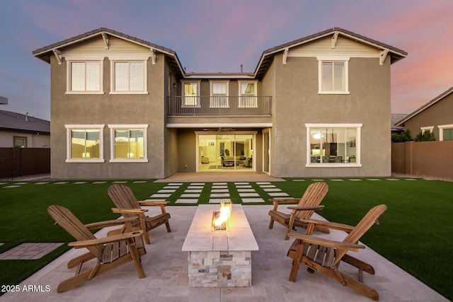 rear view of property featuring a fire pit, a patio area, a fenced backyard, and a balcony