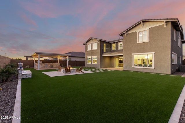 rear view of property featuring an outdoor fire pit, a patio area, a lawn, and a fenced backyard