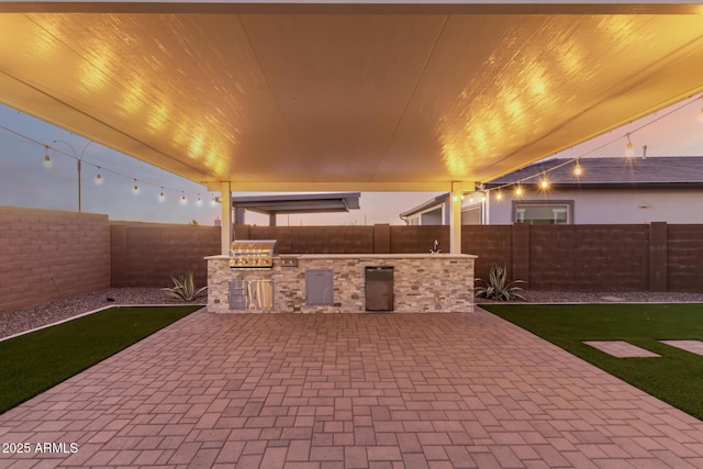 view of patio with a fenced backyard, a grill, and an outdoor kitchen