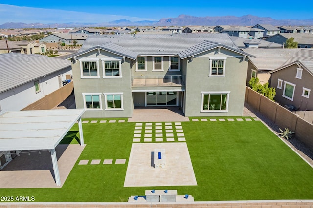 rear view of property featuring a lawn, a patio, a fenced backyard, a residential view, and a mountain view