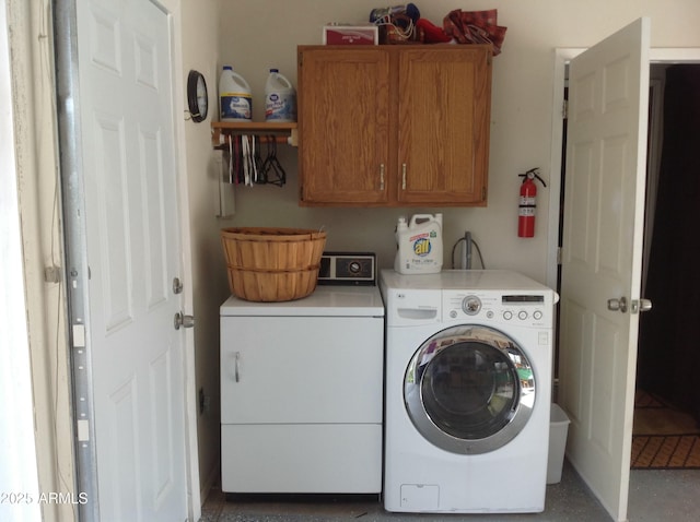 clothes washing area featuring washer and clothes dryer and cabinets