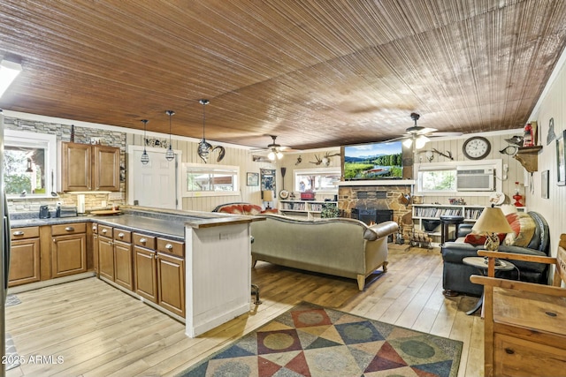 kitchen with light wood-type flooring, wooden ceiling, a stone fireplace, and a healthy amount of sunlight