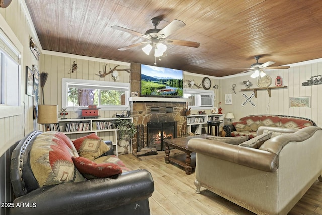 living room featuring ornamental molding, light hardwood / wood-style floors, a stone fireplace, and wooden walls