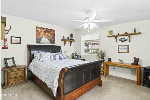 carpeted bedroom with a wood stove and ceiling fan