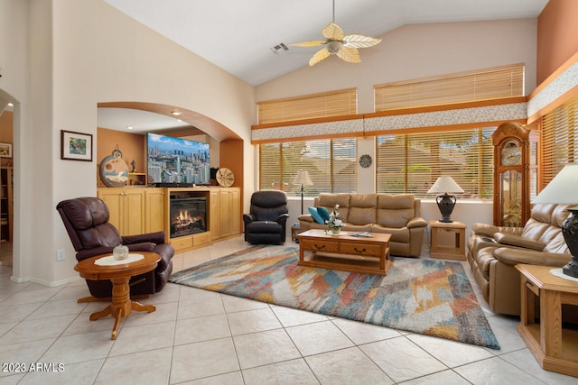 tiled living room with ceiling fan and high vaulted ceiling