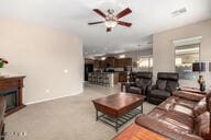 carpeted living area featuring a fireplace, baseboards, and a ceiling fan