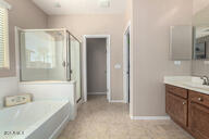 bathroom with a bath, a stall shower, baseboards, and vanity