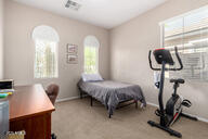 carpeted bedroom featuring arched walkways and baseboards