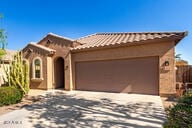 view of front of house with a tiled roof, an attached garage, driveway, and stucco siding