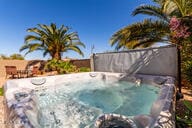 view of pool with fence and a hot tub
