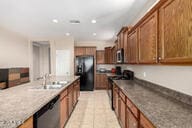 kitchen featuring brown cabinetry, freestanding refrigerator, and stainless steel dishwasher