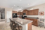 kitchen with stainless steel microwave, a breakfast bar, a kitchen island with sink, fridge, and a sink