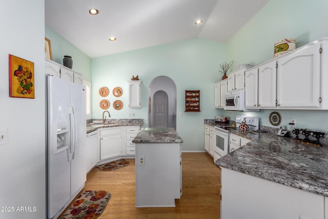 kitchen with white appliances, light hardwood / wood-style floors, a kitchen island, and sink