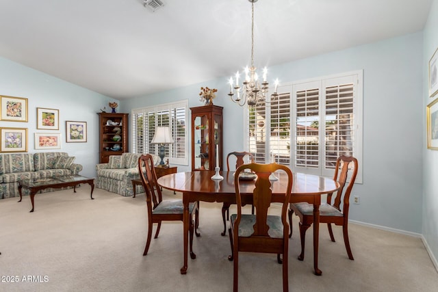 dining area with a chandelier, light colored carpet, and vaulted ceiling