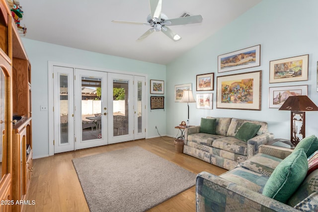 living room featuring ceiling fan, vaulted ceiling, light wood-type flooring, and french doors