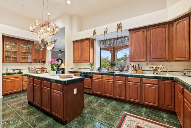 kitchen featuring a chandelier, tile counters, a center island, sink, and hanging light fixtures