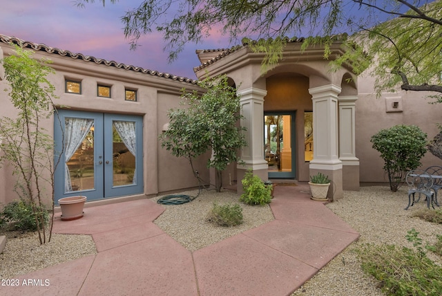 back house at dusk with french doors and a patio area