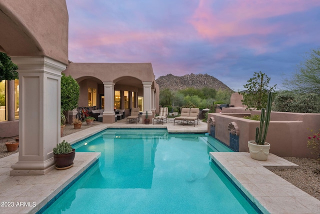 pool at dusk featuring a mountain view and a patio area