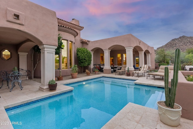 pool at dusk with a mountain view and a patio