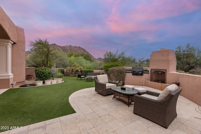 patio terrace at dusk featuring a lawn, a mountain view, and an outdoor living space