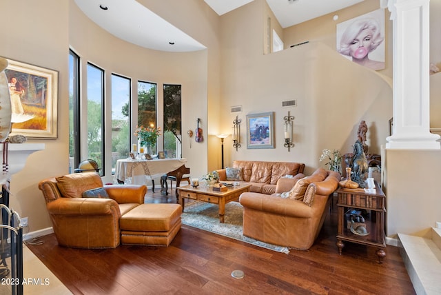 living room featuring decorative columns, a towering ceiling, and hardwood / wood-style flooring