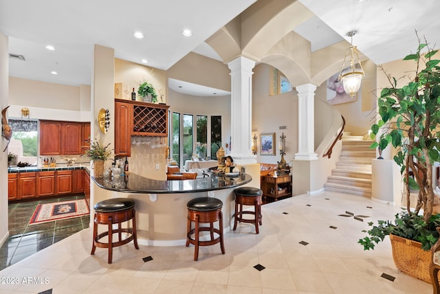 kitchen with a breakfast bar area, decorative columns, kitchen peninsula, and a healthy amount of sunlight