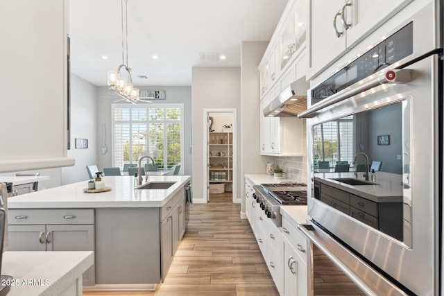 2630 E Lovebird Ln, Gilbert, AZ 85297 - kitchen with appliances with stainless steel finishes, light wood-style floors, a center island with sink, recessed lighting, and light countertops