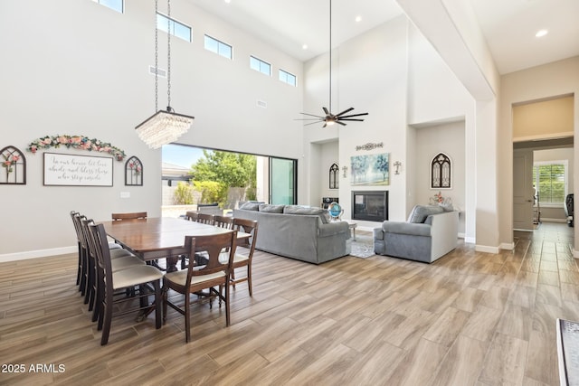 2630 E Lovebird Ln, Gilbert, AZ 85297 - dining room with light wood-style flooring, a towering ceiling, a glass covered fireplace, recessed lighting, and a ceiling fan