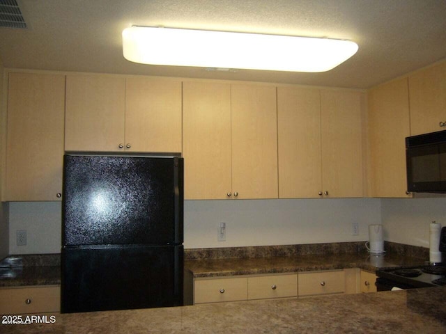 kitchen featuring visible vents, black appliances, and dark stone counters