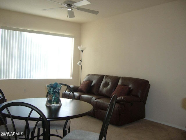 carpeted living area with a ceiling fan