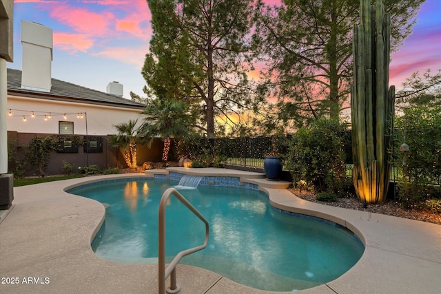 pool at dusk with a patio and pool water feature