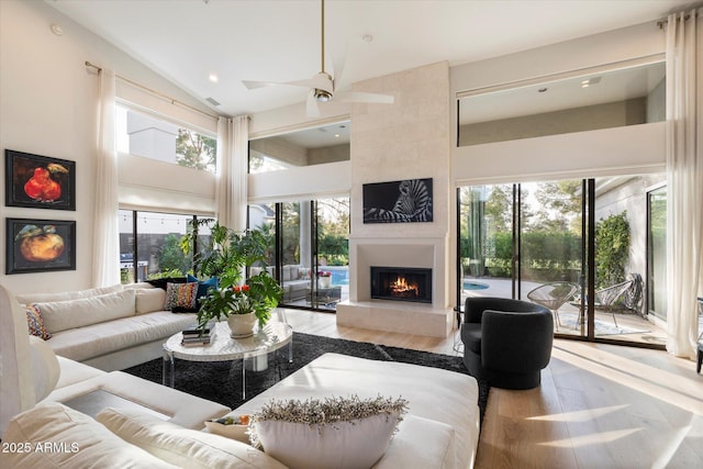 living room with hardwood / wood-style floors, a tile fireplace, a healthy amount of sunlight, and ceiling fan