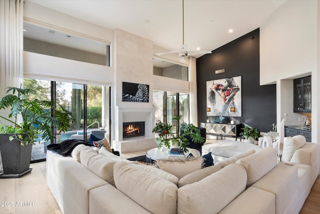 living room with light hardwood / wood-style flooring, a towering ceiling, and a fireplace